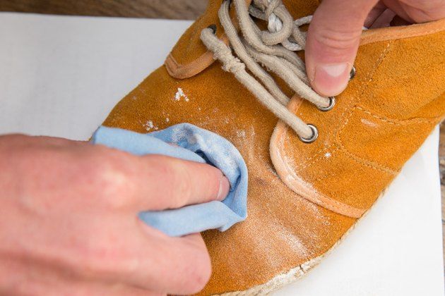 a person is cleaning a pair of brown shoes with a blue cloth on the floor