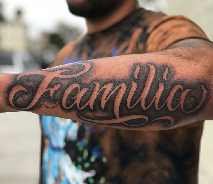 a man is holding his arm with the word familiaa tattooed on it