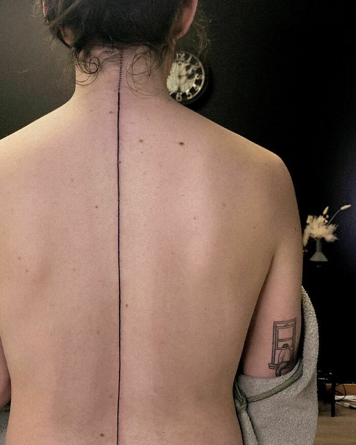 the back of a woman's body with tattoos on her upper and lower back