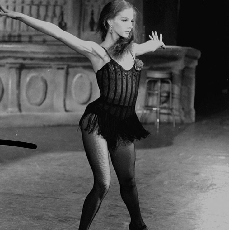 a black and white photo of a woman in a leotard with her arms outstretched