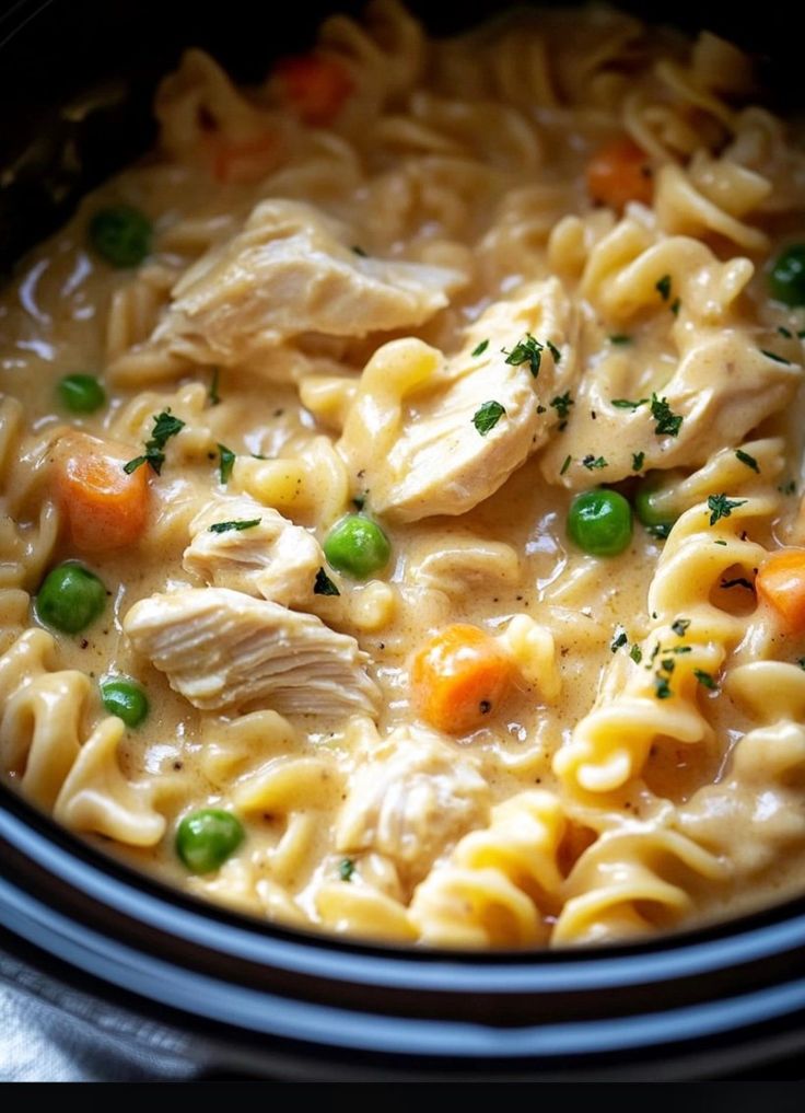 chicken noodle soup with carrots and peas in a slow cooker