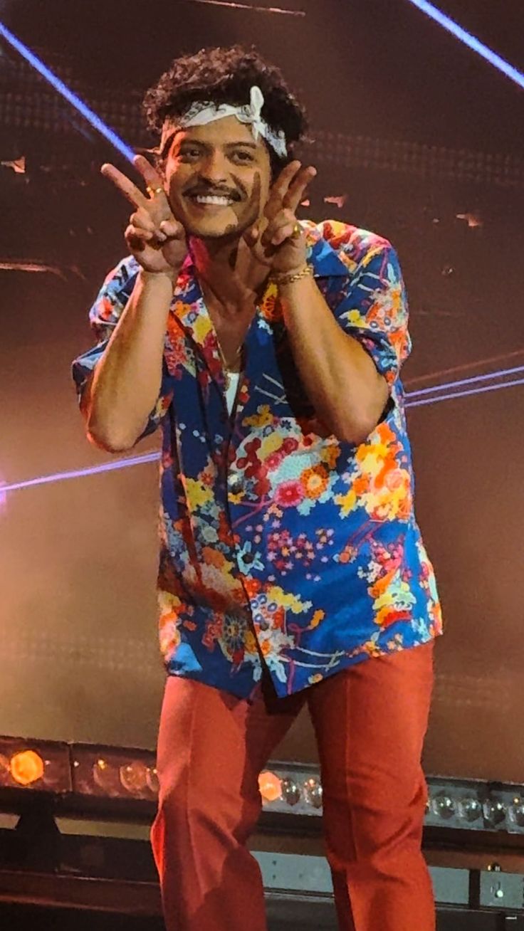 a man standing on top of a stage with his hands in the air and smiling