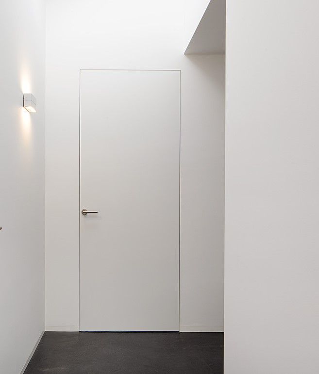 an empty room with a white door and some lights on the side of the wall