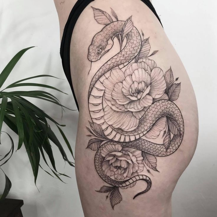 a woman's thigh with a snake and roses tattoo on it