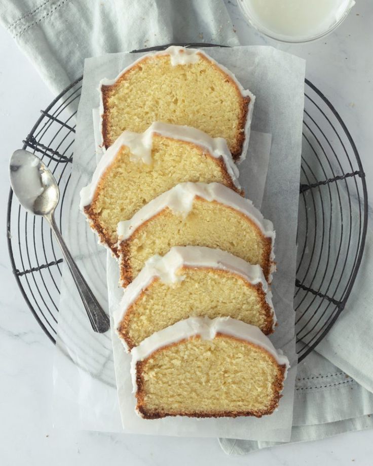 slices of lemon pound cake with icing on a plate next to a glass of milk