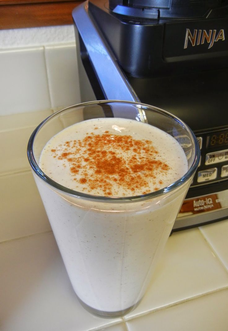 a glass filled with liquid sitting on top of a counter next to a blender