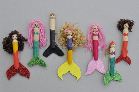 a group of mermaid dolls sitting next to each other on top of a gray surface