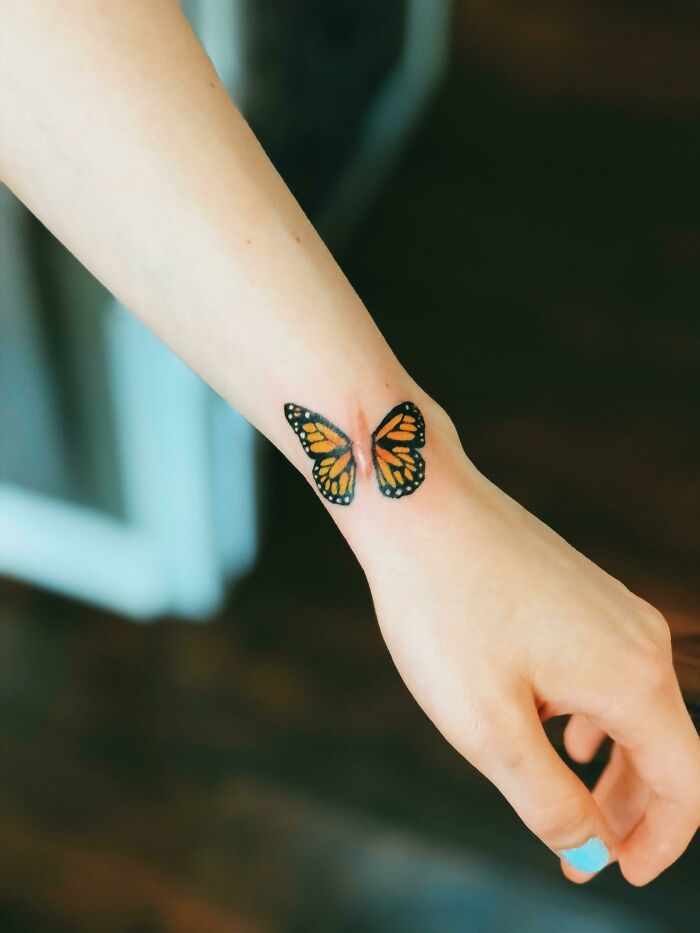 a woman's arm with two butterfly tattoos on her left wrist and the other hand