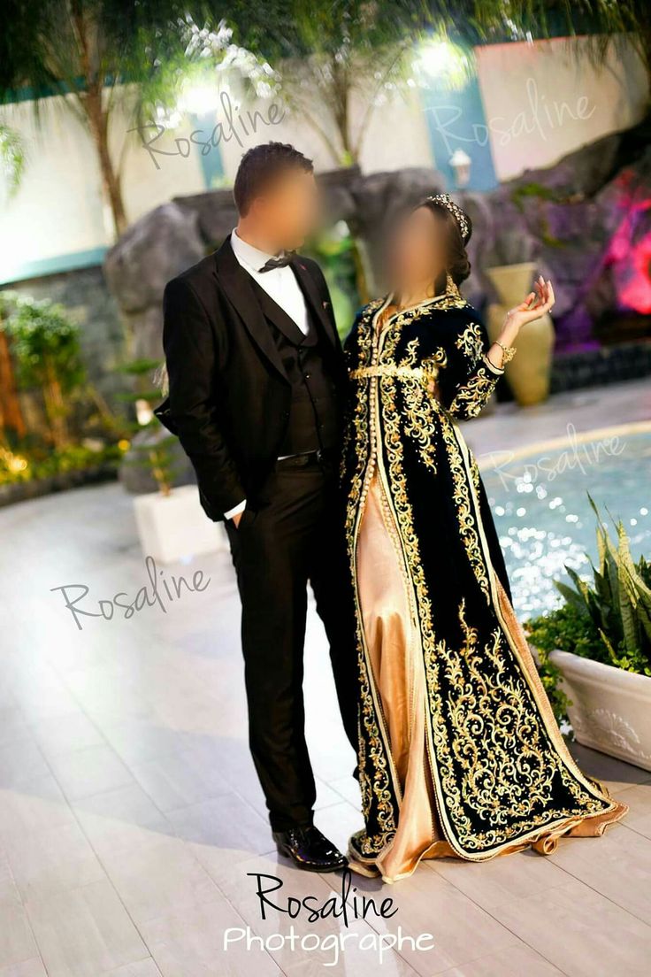 a man and woman standing next to each other in front of a fountain at night