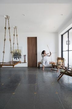 a woman is standing in an empty room with swings and paintings on the wall behind her