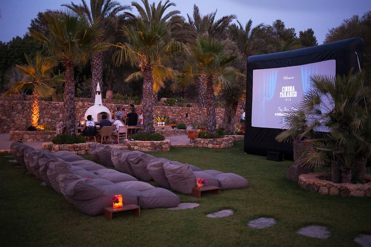 an outdoor movie is set up on the lawn with lounge chairs and palm trees in the background