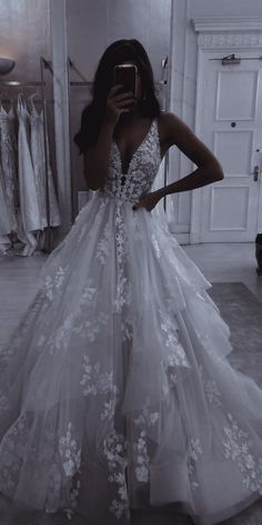 a woman taking a selfie in a wedding dress with flowers on the skirt and back