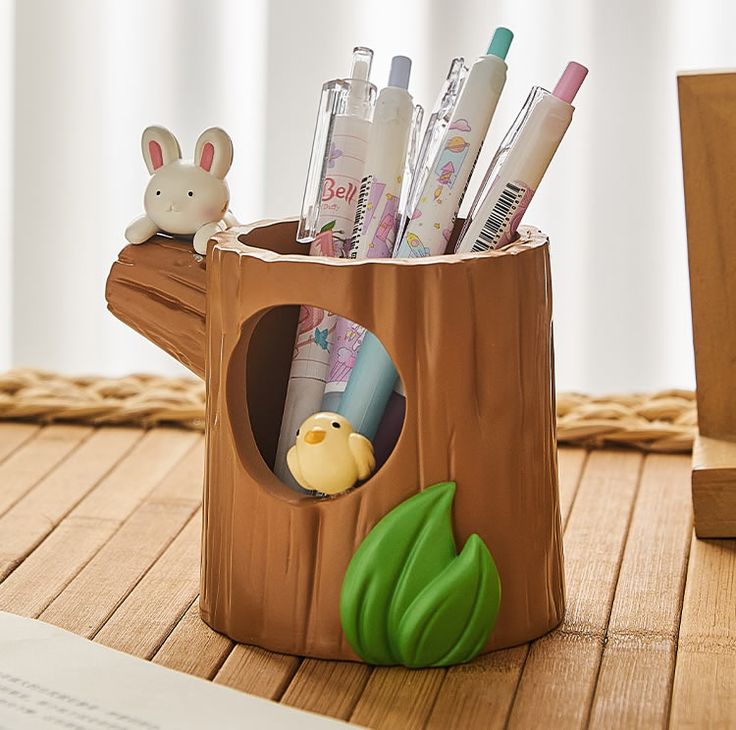 a pen holder with pens and pencils in the shape of a tree stump on a wooden table