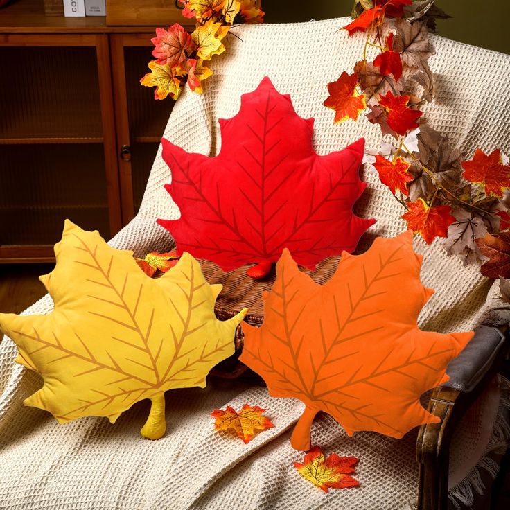 three autumn leaves are laying on a chair