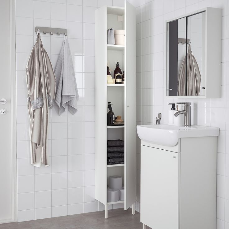 a bathroom with white walls and tile flooring is pictured in this image, there are towels hanging on the wall