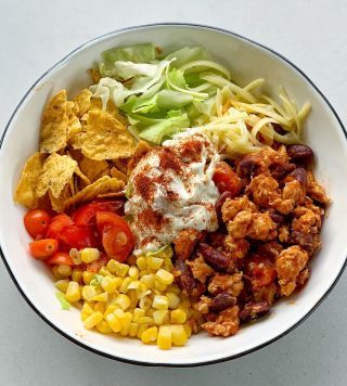 a bowl filled with different types of food on top of a white table next to a fork