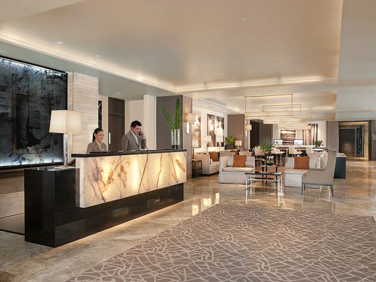 a hotel lobby with two people standing at the front desk