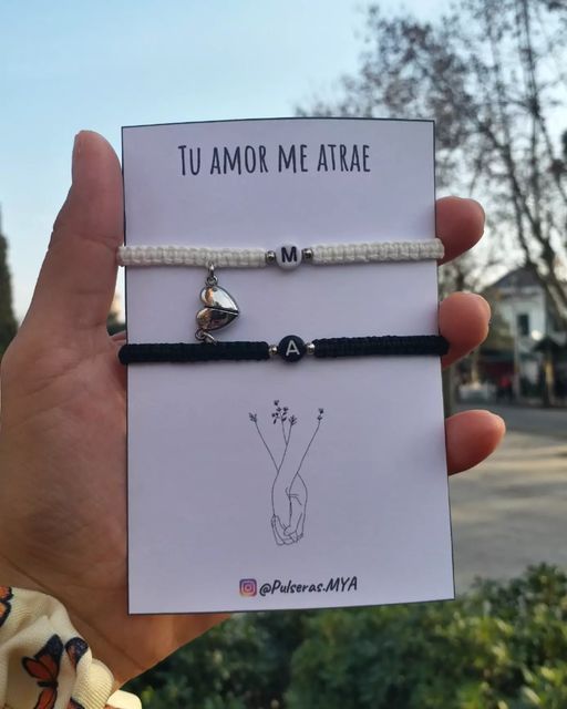 a person holding up a card with two bracelets on it and the words tu amor me ariae