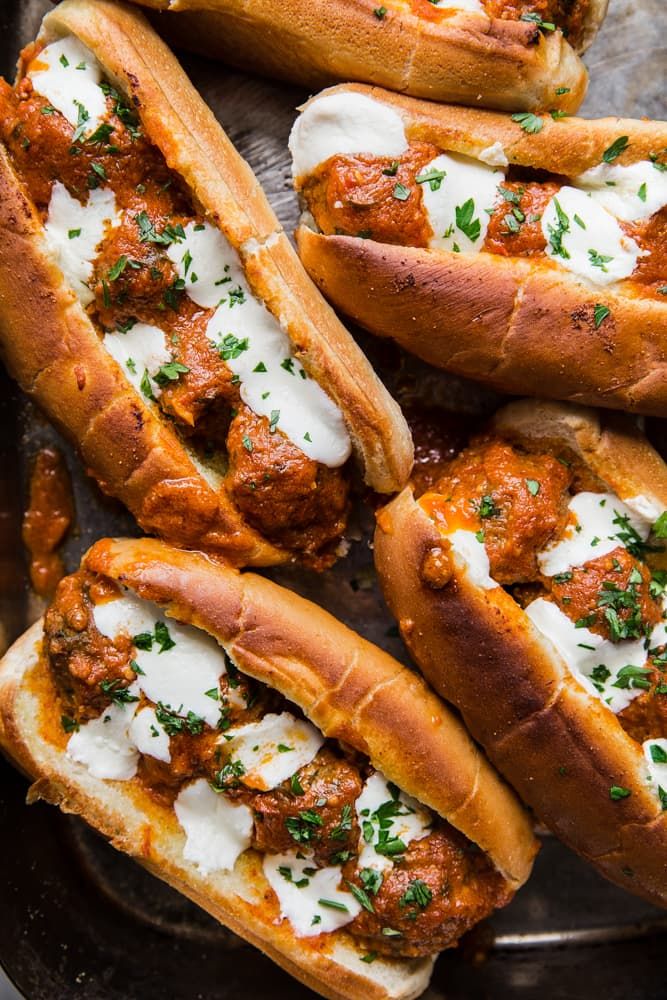 several hot dogs covered in sauce and cheese on a plate with breadsticks next to them