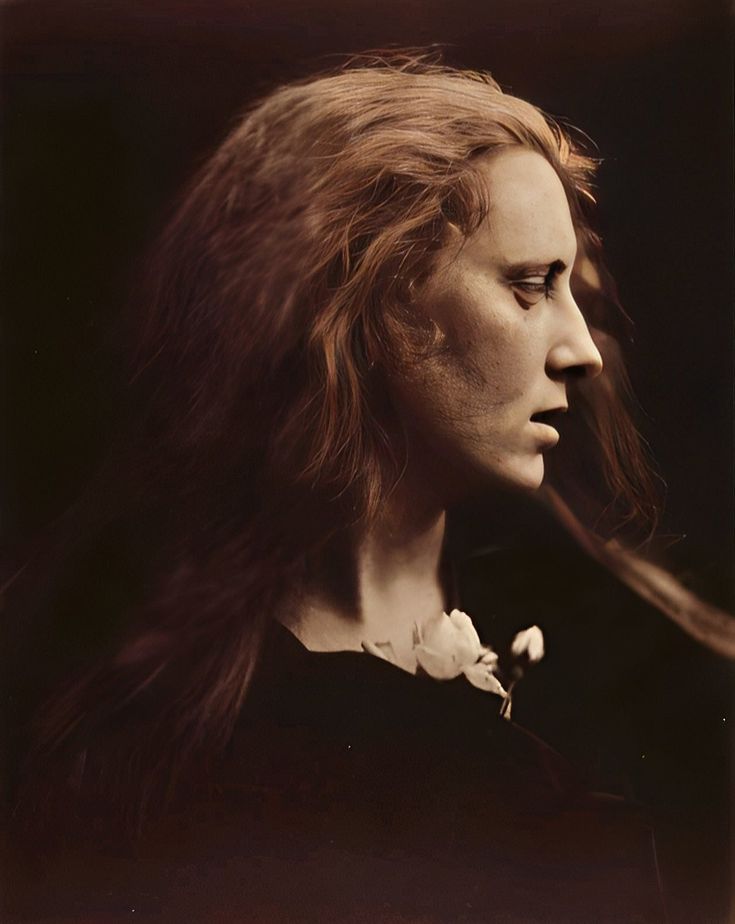 an old photo of a woman with long hair blowing in the wind and looking to her left