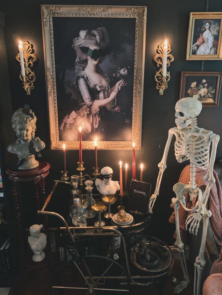 a table with candles and skeleton figurines in front of a painting on the wall