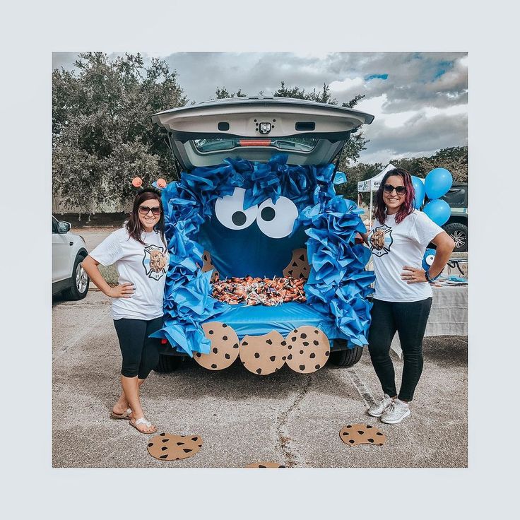 two women standing in front of a car decorated with blue and white decorations on the hood