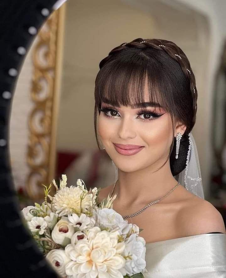 a woman in a wedding dress holding a bouquet and looking at the camera with a smile on her face