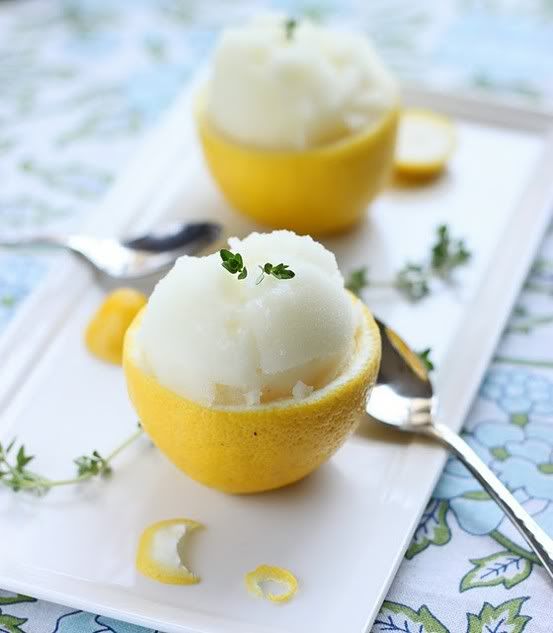 two lemons with ice cream in them sitting on a plate next to a spoon