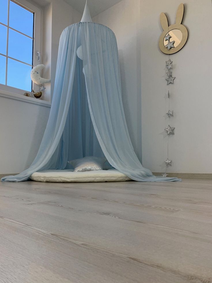 a bed that is in the middle of a room with a blue canopy over it