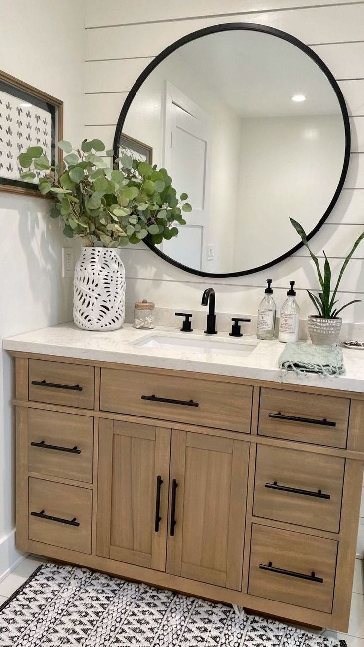 a bathroom with a large round mirror above the sink and wooden cabinetry on the wall