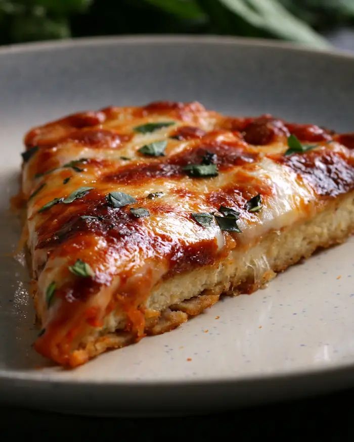 a slice of lasagna on a plate with parmesan cheese and herbs