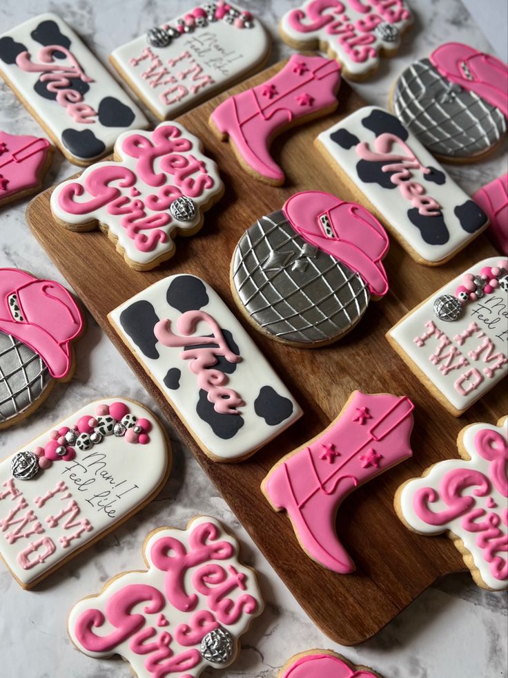 decorated cookies with pink and black designs on a cutting board next to some other decorations