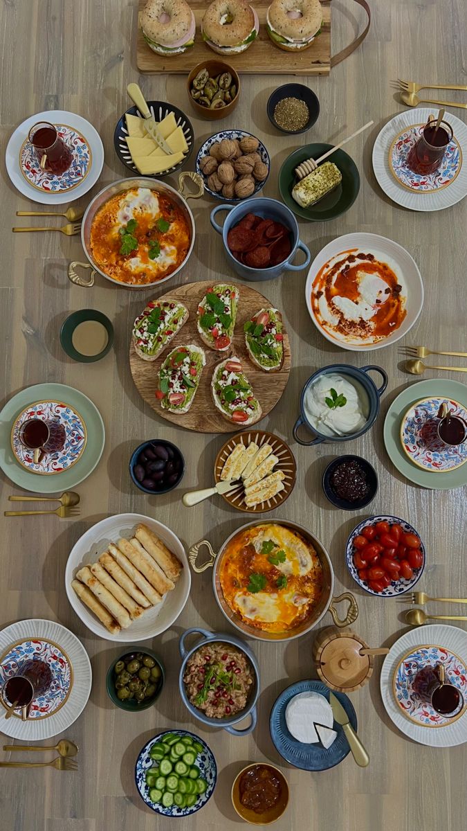 a table filled with lots of food on top of a hard wood floor covered in plates and bowls