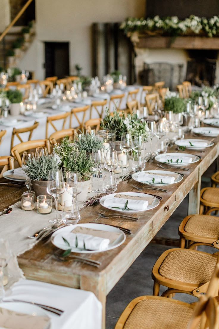 a long table set with place settings and greenery