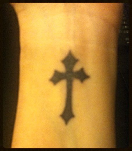 a cross tattoo on the foot of a person