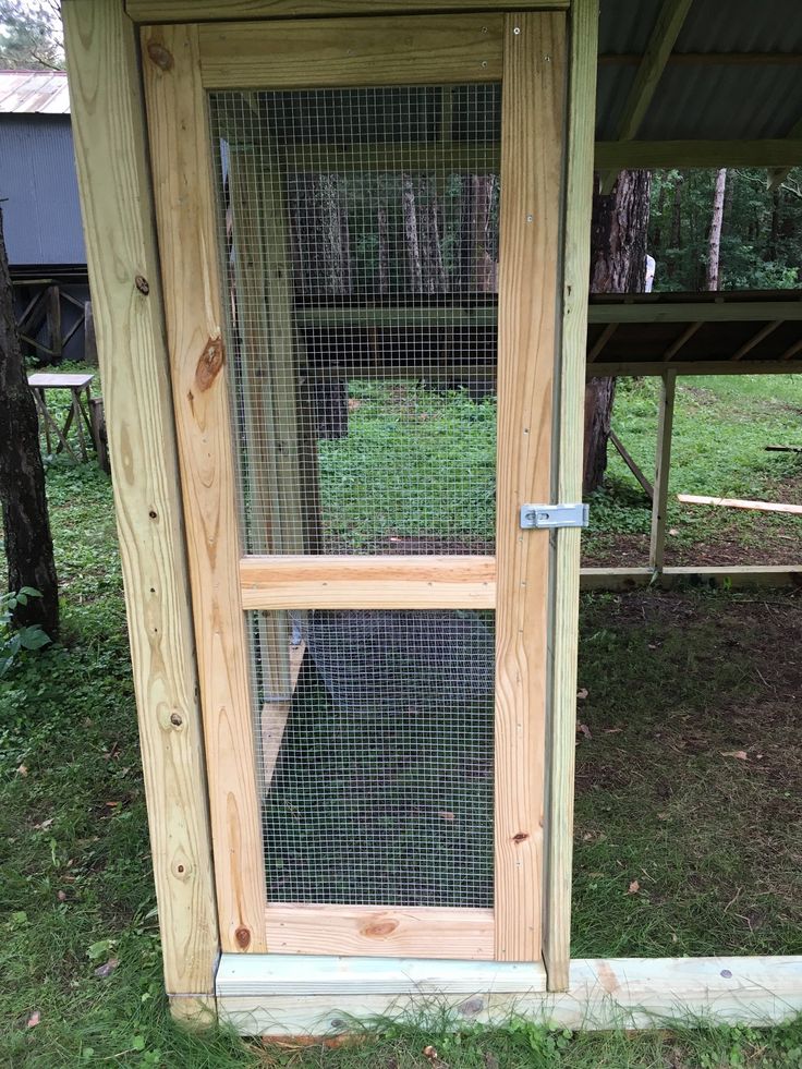 a chicken coop built into the side of a wooden building with a wire door and window