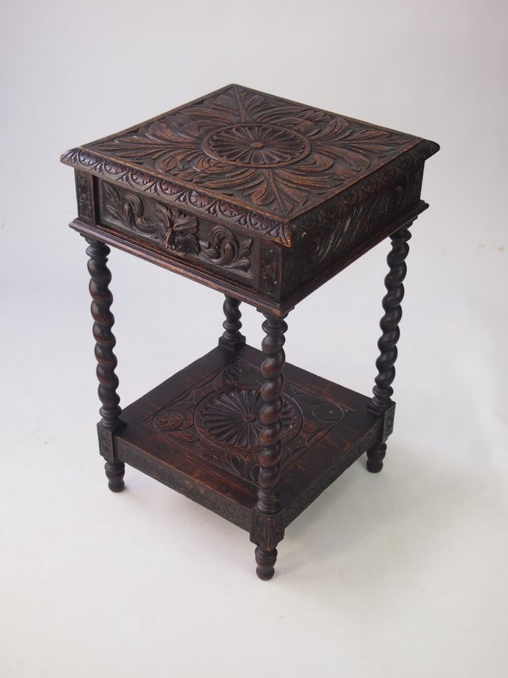 an antique wooden table with carved designs on it's sides and one drawer at the top