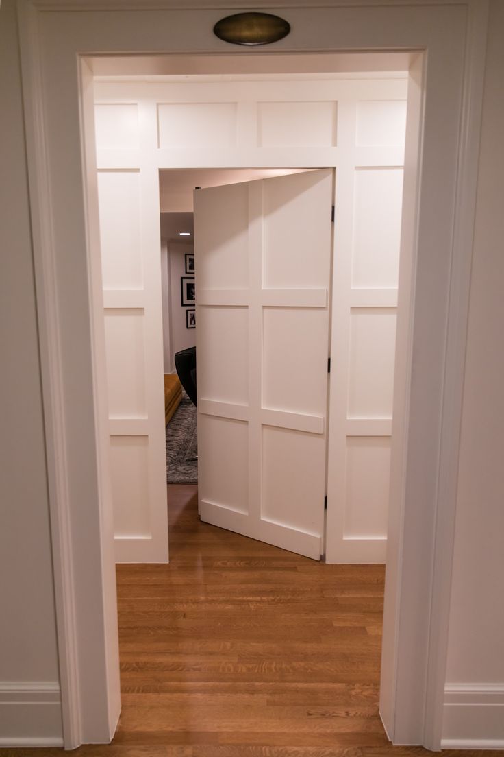 an open door leading to a living room with hard wood flooring and white walls