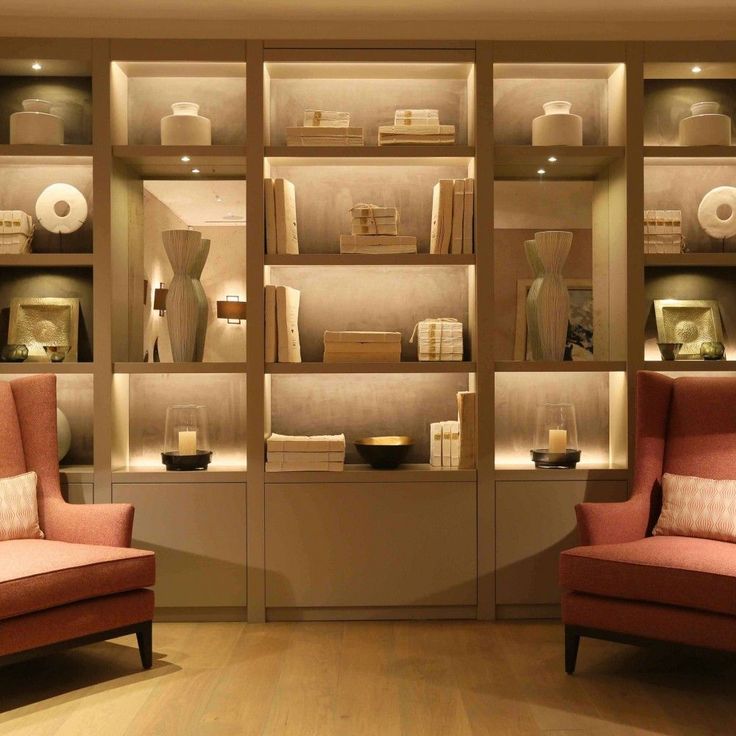 two red chairs sitting in front of a bookshelf