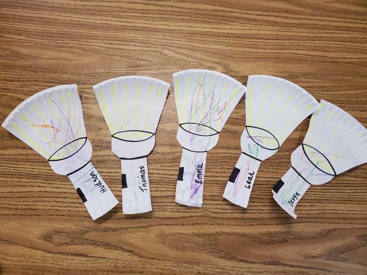 four paper fans with writing on them sitting on a wooden table next to each other