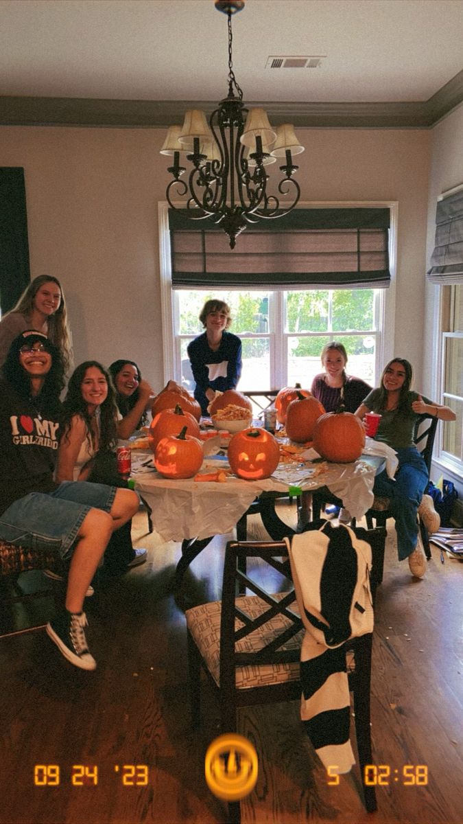 a group of people sitting around a table with pumpkins