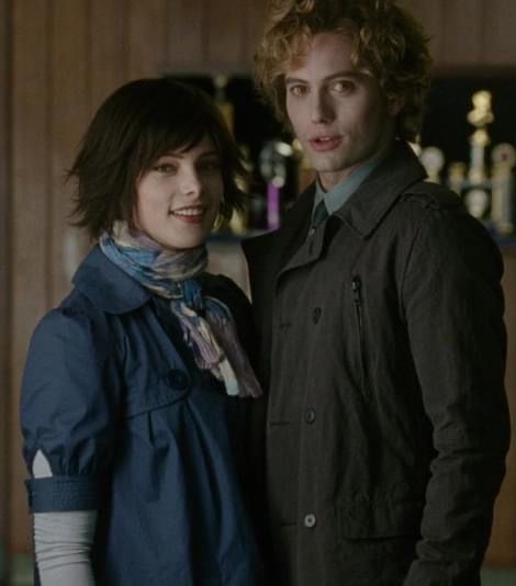 a man and woman standing next to each other in front of a shelf with bottles on it