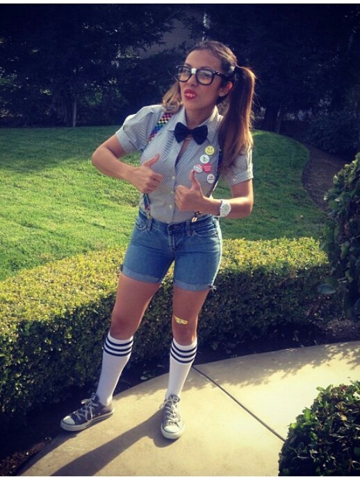 a woman in shorts and socks is standing on the sidewalk with her hands behind her back