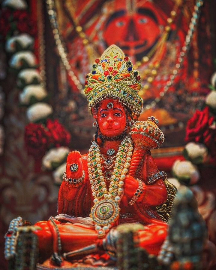 a statue of hindu god sitting in front of a painting