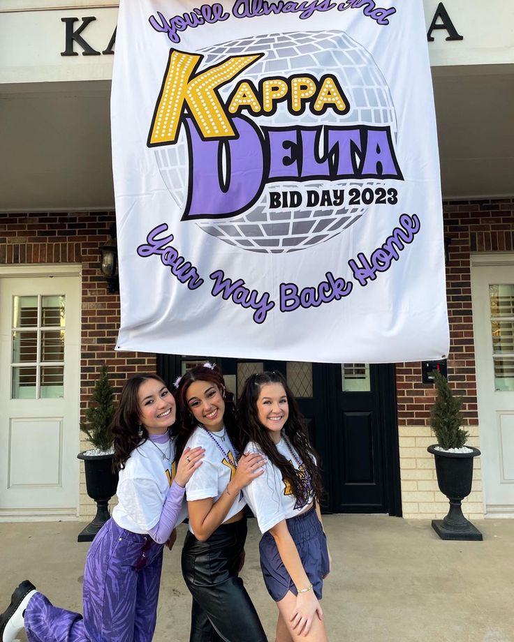 three girls standing in front of a sign for the kapa delna bida