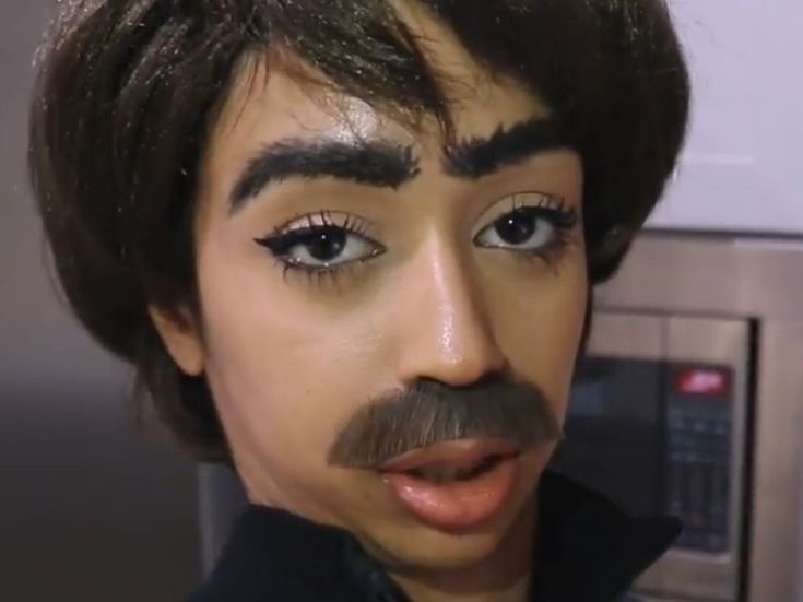 a close up of a man with fake eyebrows and mustaches on his face, in front of a microwave