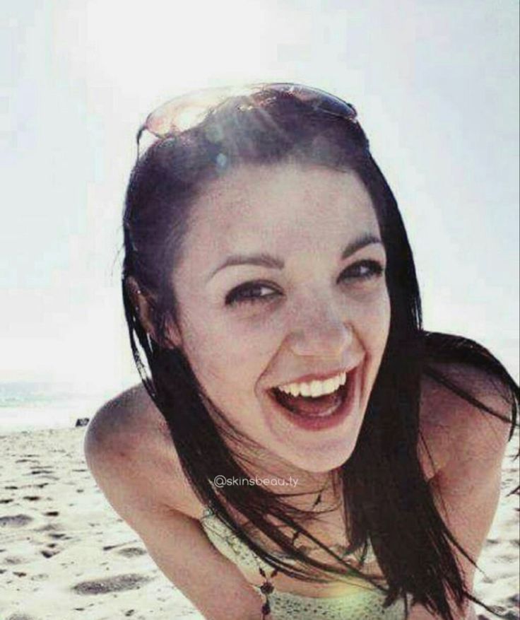 a woman laying on top of a sandy beach next to the ocean with her mouth open