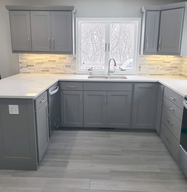 a kitchen with gray cabinets and white counter tops, an oven and dishwasher