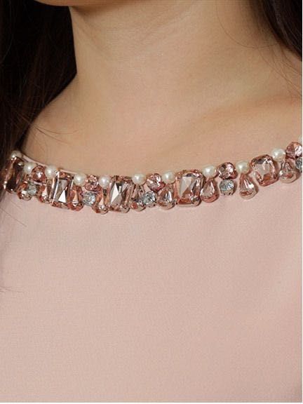 a close up of a woman wearing a pink dress with pearls on the neck and necklace