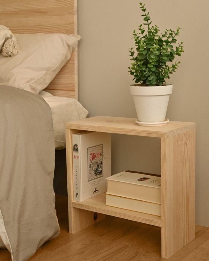 a bed with a plant on top of it next to a nightstand